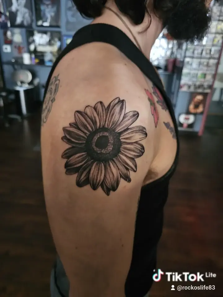 Black and gray sunflower tattoo on an upper arm